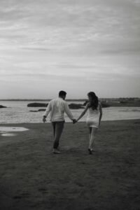 Beautiful couple walking hand-in-hand on the beach, symbolizing love, connection, and balance in midlife.